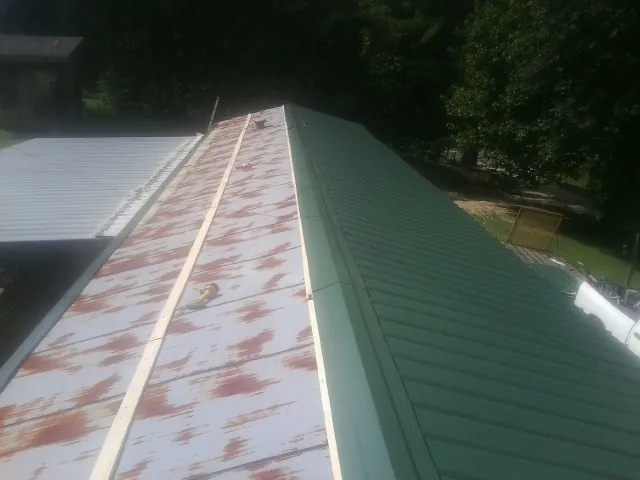 Old rusted panels beside newly installed green metal roofing — Wind Damage Roof Repair by Roofing Brothers in Woodrow