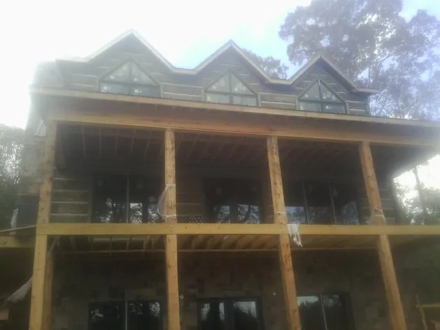 Dormers and porch framing on a large log home under construction — Roof Coating work by our crew in Woodrow