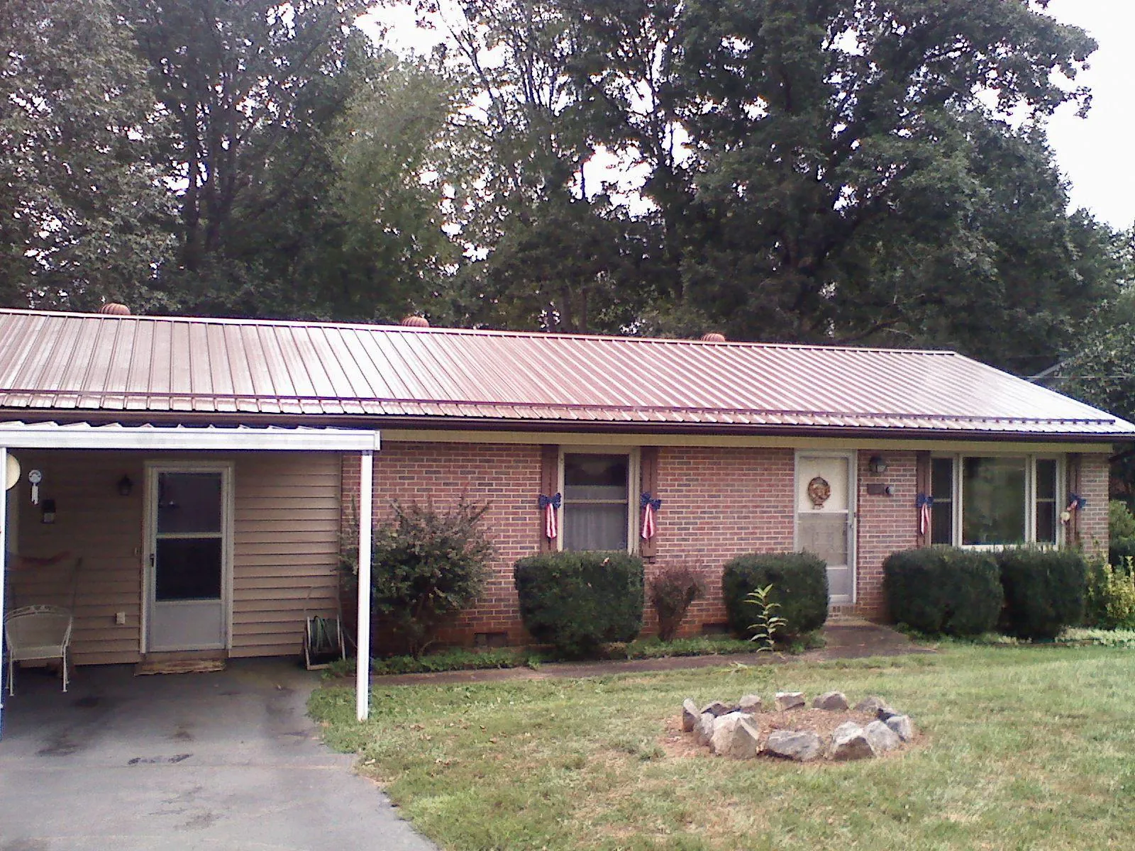 Bronze metal roof and carport on a brick ranch home — Roof Repair work by our crew in Woodrow