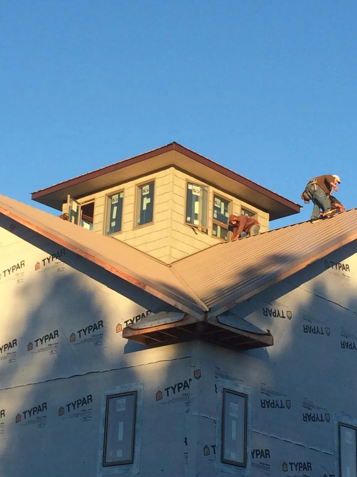 Roofers working around a rooftop cupola on a new metal roof at sunset — Roof Waterproofing in Woodrow by Roofing Brothers